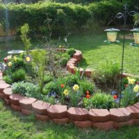 Parterre de fleurs faite maison avec des bordures de tuiles