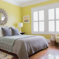 Žuti zidovi i sive prekrivače u spavaćoj sobi 12 četvornih metara