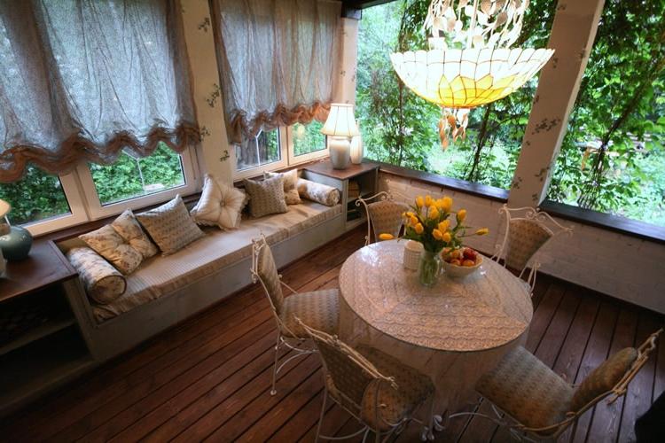 Dining table and soft sofa on the veranda of the country house