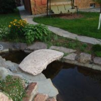 Ponticello di pietra sopra un flusso del giardino