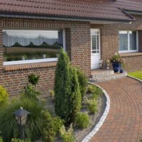 Flowerbed with conifers in front of a window of a country house