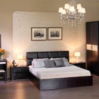 Black bed with a white bedspread in a room with light walls