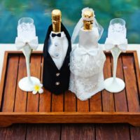 Vjenčane boce šampanjca na drvenom pladnju