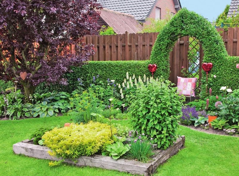 Wooden flowerbed on the lawn in front of the garden entrance