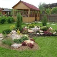 A flowerbed of stones and a gazebo in the background