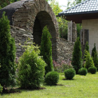 Clôture en pierre avec une arche à l'entrée du chalet