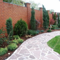 Path covered with natural stone along a brick fence