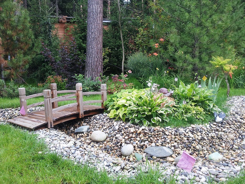 The bed of a dry stream passing around a flower bed