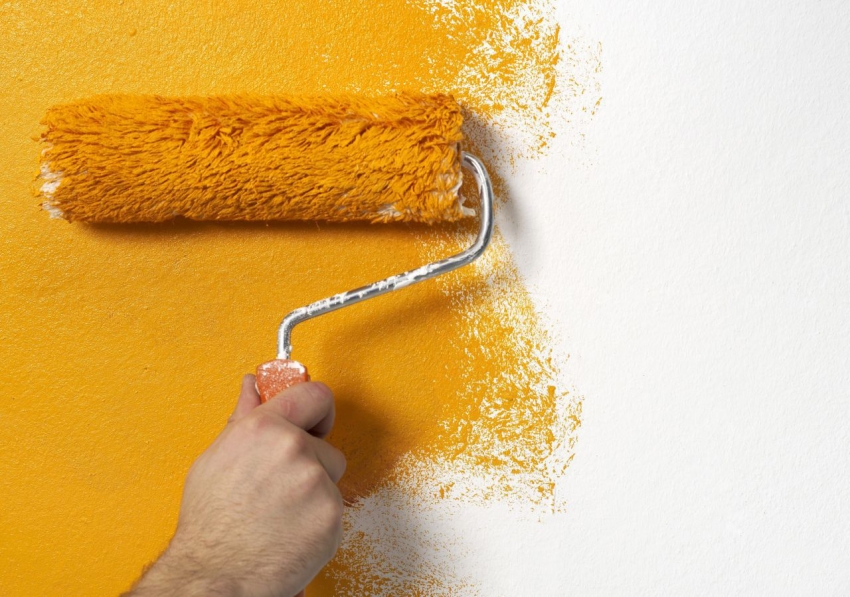 Painting wallpaper on the wall with a roller in orange