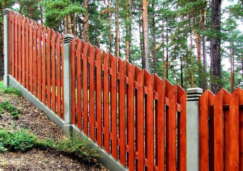 Recinzione in legno sul pendio di un cottage estivo