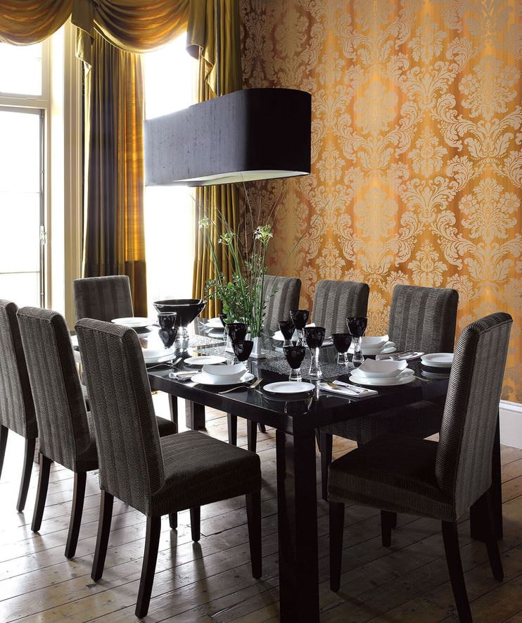 Black chairs at the dining table in a room with dark gold wallpaper