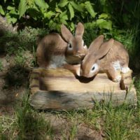 Figure di lepri con un alimentatore per decorare il giardino