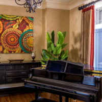 Black piano in front of the living room window