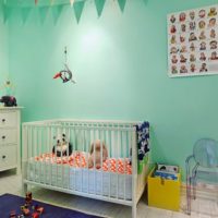 Crib for a newborn in front of a mint color wall