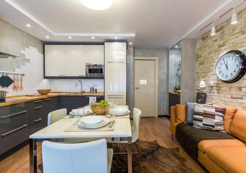 Orange sofa along the wall in the kitchen-living room with stone cladding