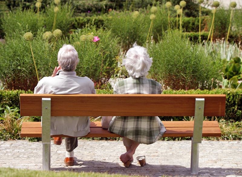 Personnes âgées se détendre sur un banc en bois dans un parc de loisirs