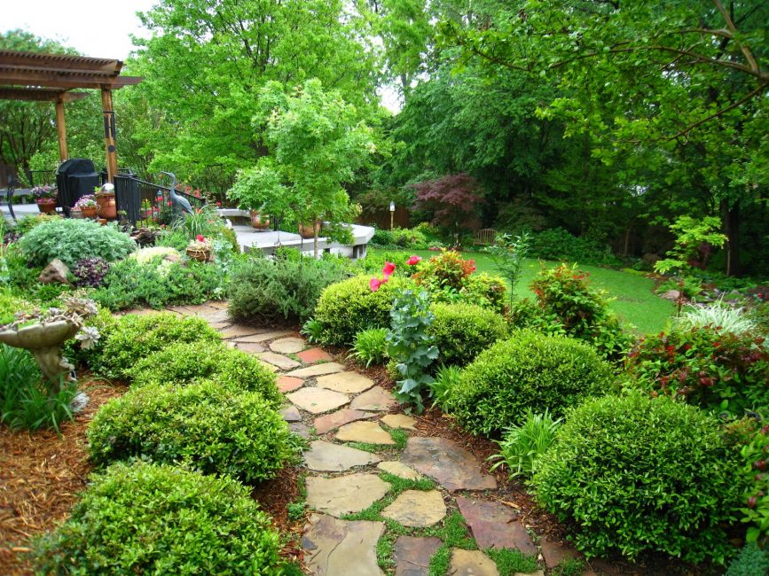 Allée de jardin en pierre naturelle menant à un kiosque en bois