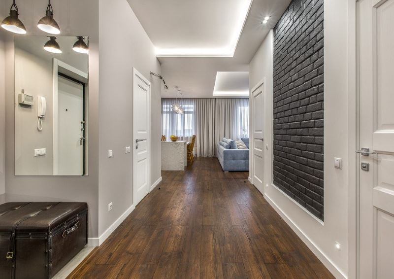 Dark gray brick wall in the interior of a narrow corridor with white doors