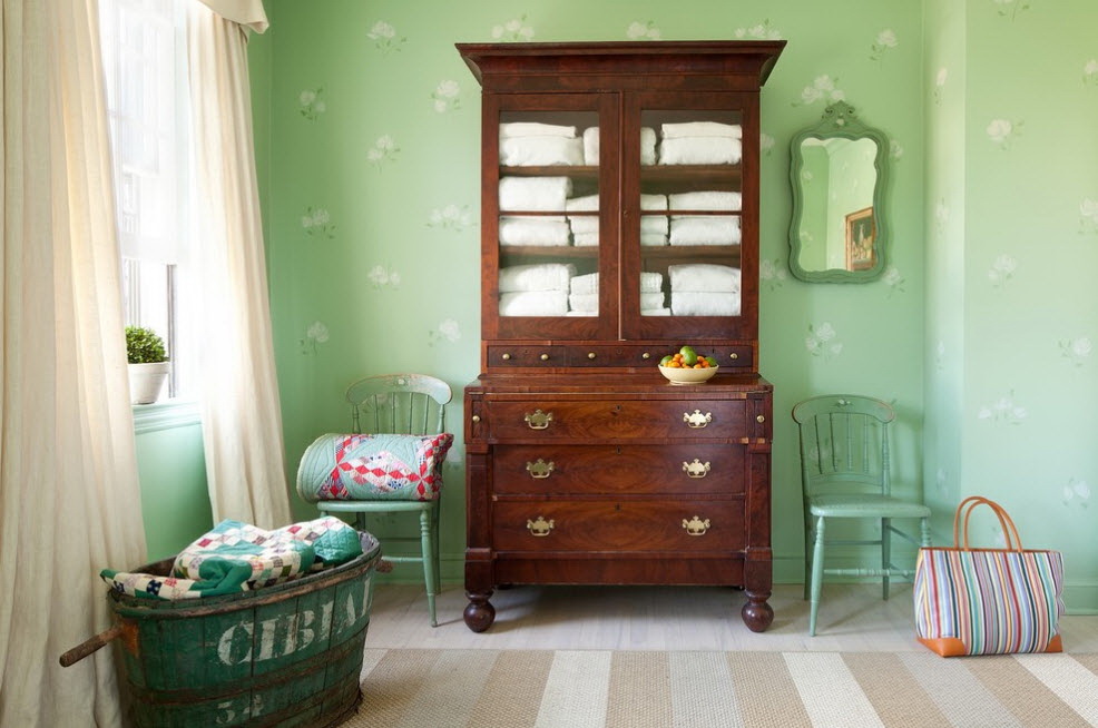 Brown chest of drawers on a background of green wallpaper