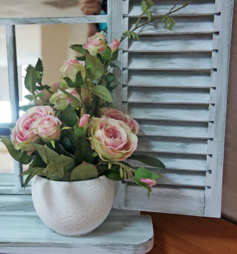 Lonac cvjetajućih ruža na drvenom prozoru