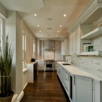 Two rows of spotlights on the ceiling of a narrow kitchen