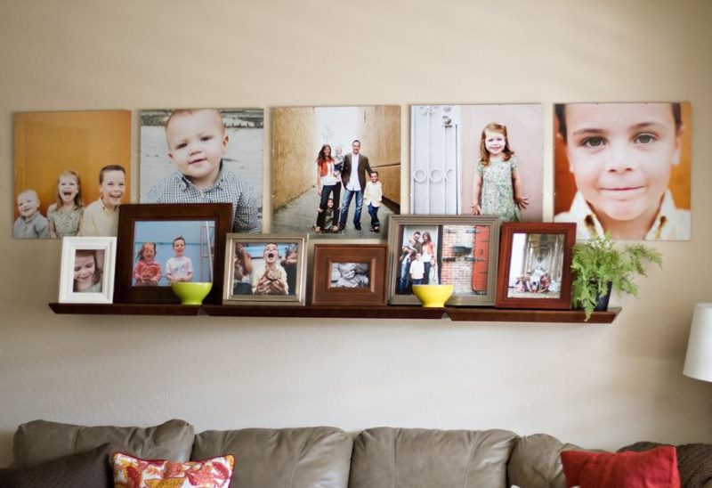 Polica s obiteljskim fotografijama na zidu dnevne sobe