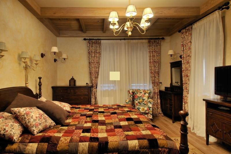 Small chandelier on the ceiling of a bedroom with two windows