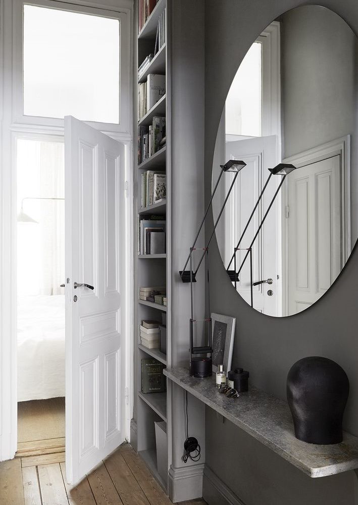 Ovalno ogledalo na sivom zidu hodnika