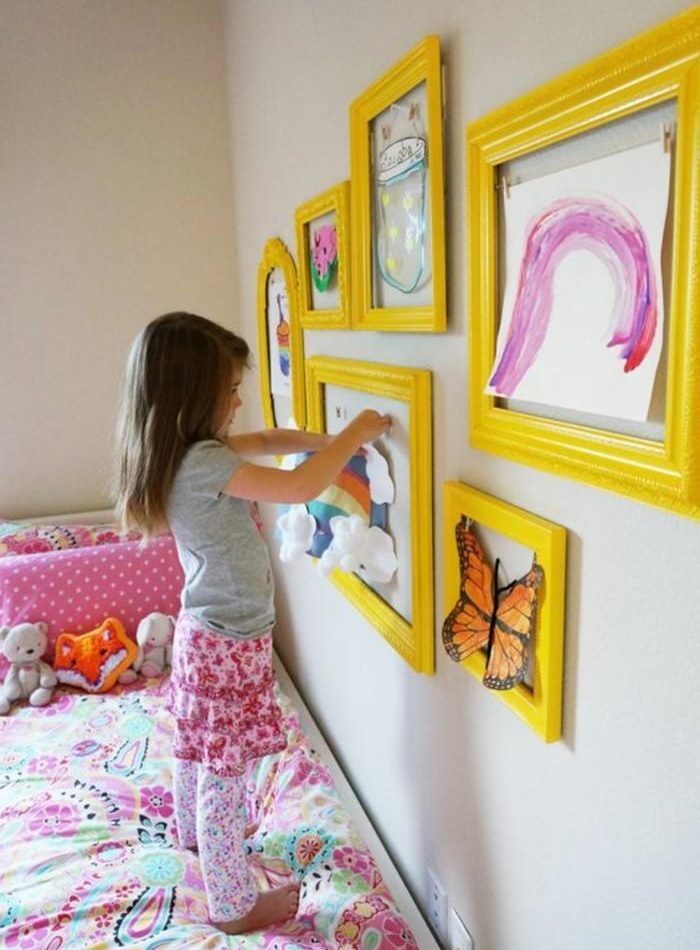 Djevojka ukrašava sobu vlastitim crtežima.