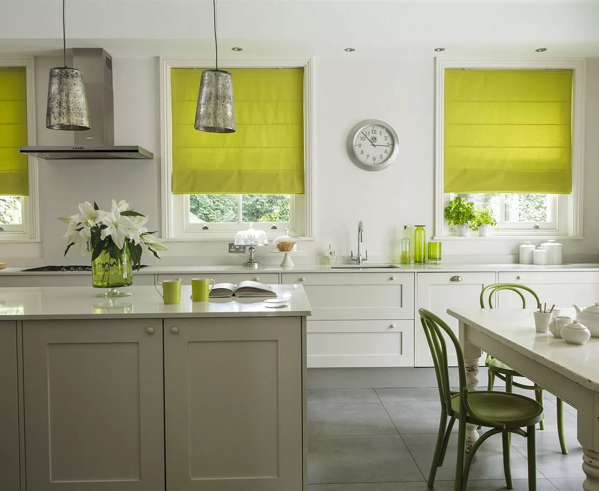 Clock on the wall between windows with roman blinds