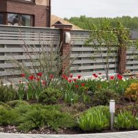 Wooden fence on pillars made of facing bricks