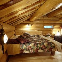 Unutrašnjost spavaće sobe s niskim stropom u kući od brvnara