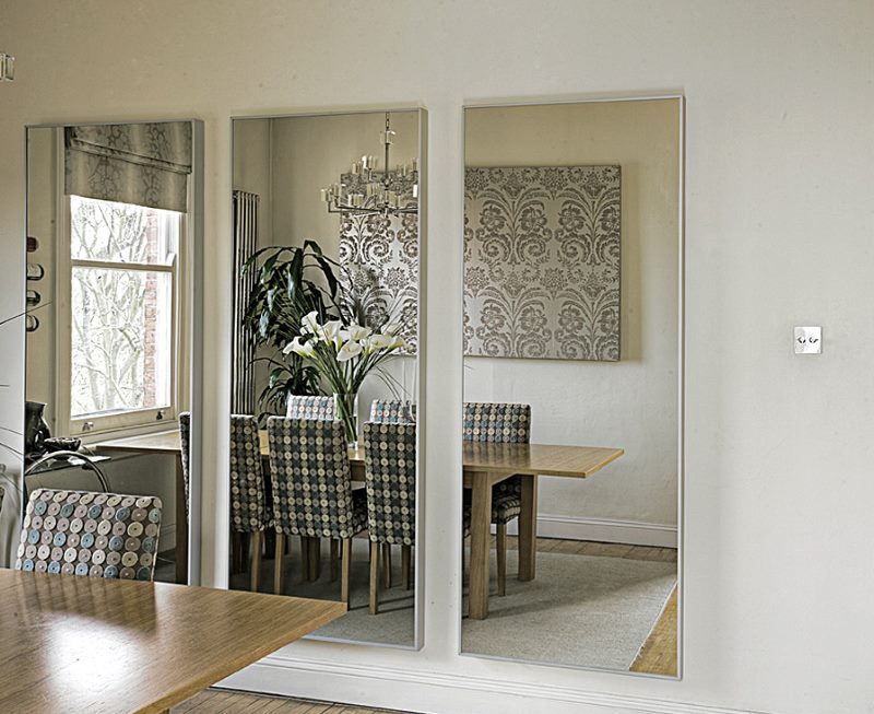 Trois miroirs sans cadres sur le mur de la cuisine-salle à manger