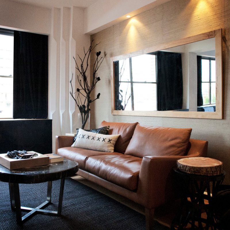 A large mirror above the leather sofa in the living room