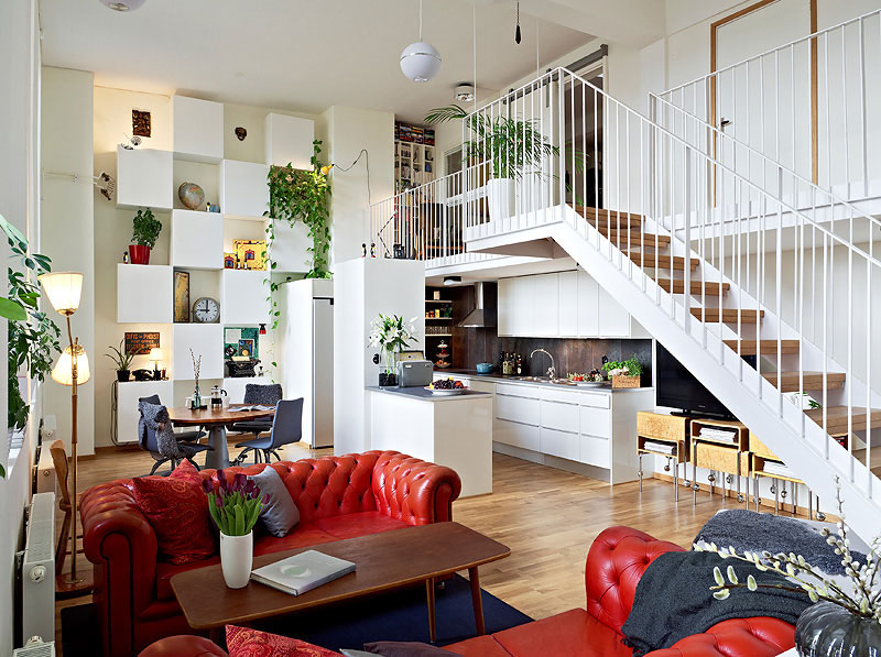 Escalier blanc dans le salon avec canapés rouges.