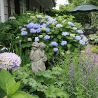 Sculpture de jardin sur un fond d'hortensia à fleurs lilas